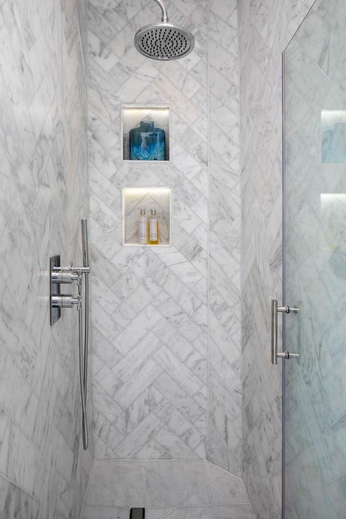 Bathroom with herringbone marble shower tiling and recessed niches