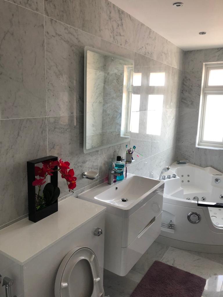 En-suite vanity unit and basin with marble-effect wall tiles