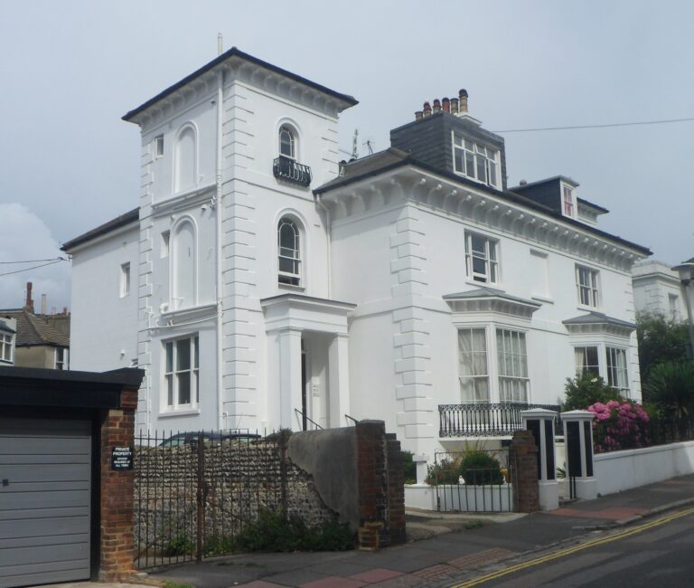Painted white render terraced house with sash windows and railings